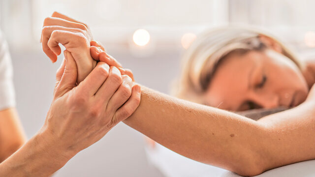 A Woman enjoying spa treatment at salon with masseur worker Eine Armmassage